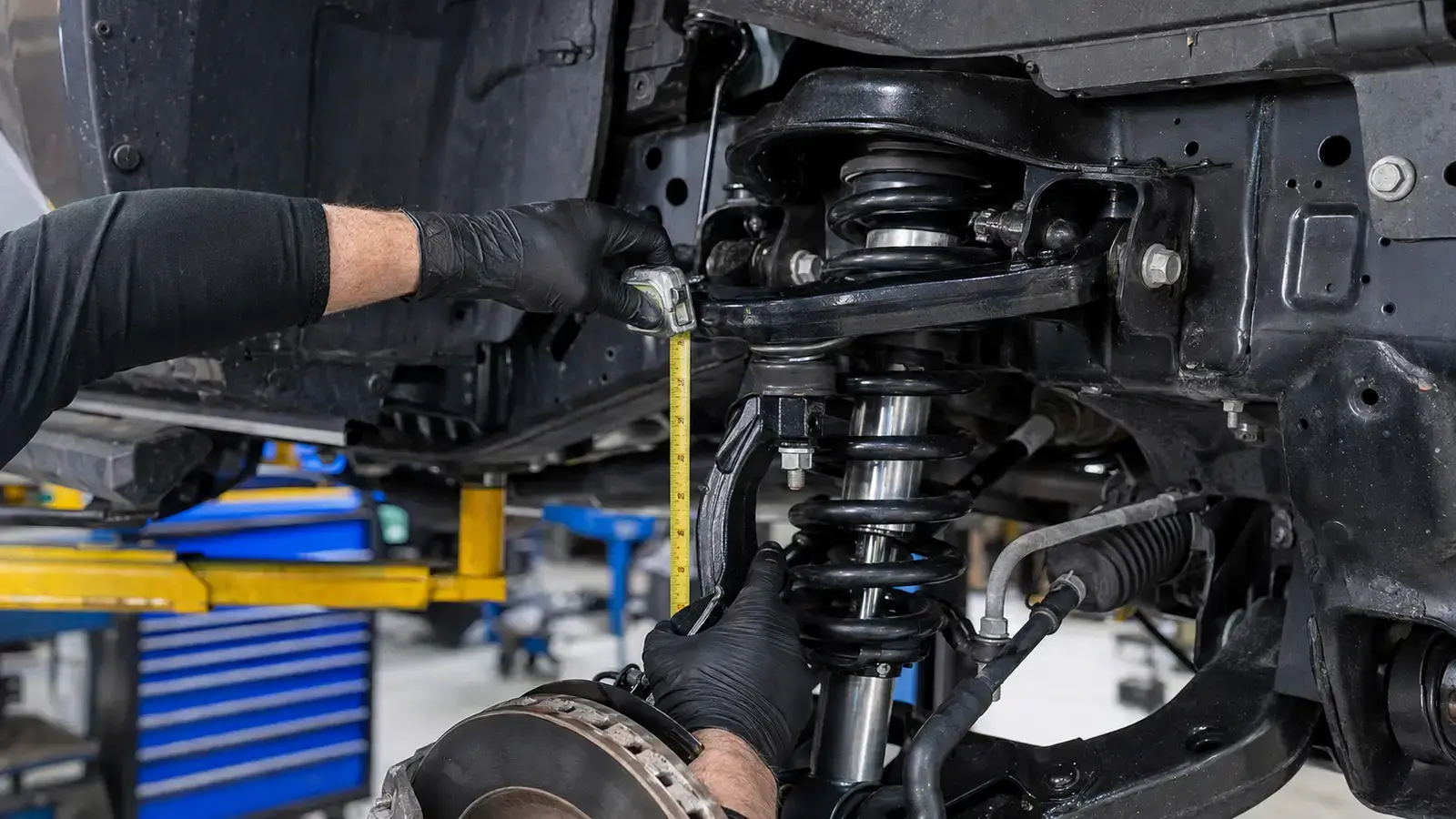 Mechanic measuring suspension clearance during a truck lift-kit installation