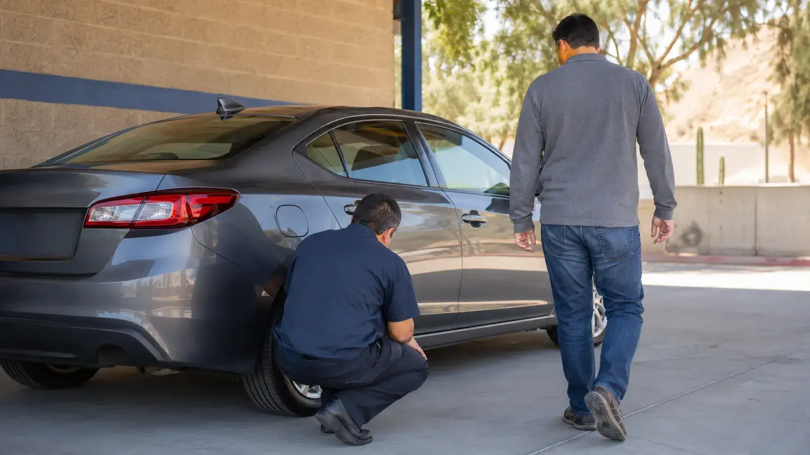 Buyer and mechanic checking a used sedan before purchase